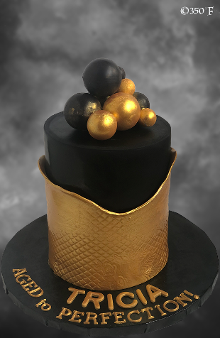 gold and black chocolate orbs on a birthday cake