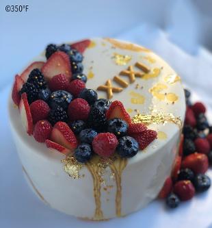 mirror glaze cake with fresh berries and 24K gold leaf decorations