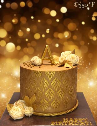 gold monogram birthday cake with white gilded roses