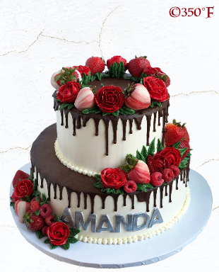 Two round tier cake with chocolate drip, red flowers, and strawberries