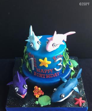 baby shark themed tiered cake for a double birthday celebration with 3D models of the shark family