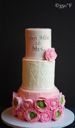 A bridal shower tiered cake adorned by sugar ranunculuses