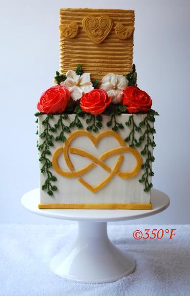 A two tier buttercream wedding cake with lovebirds, roses and infinite love monogram