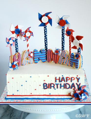 A july 4th theme birthday cake complete with edible pinwheels and the birthday girl's name in cookie art.
