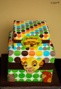 A Lion King themed tiered baby shower cake with multicolored polka dots