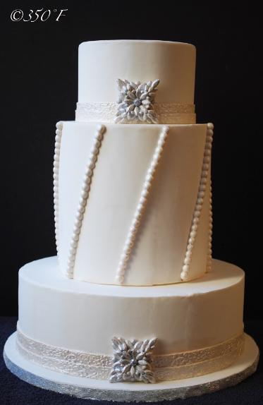 A jeweled wedding cake with ornate brooch and pearl strings