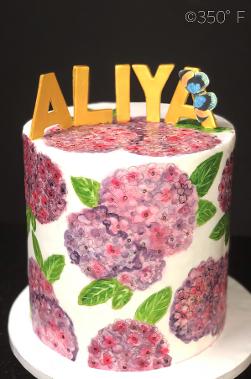 Queens, NY round tier cake with pink and purple hydrangea flowers and gold letters
