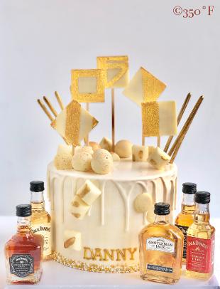 Cream and gold round tier cake with mini liquor bottles in NYC