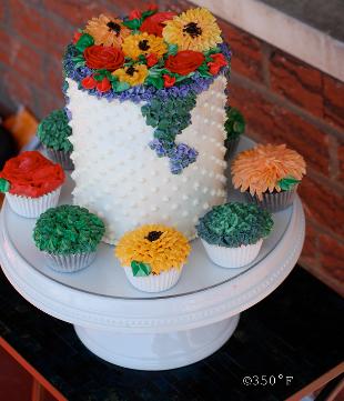 A cake and cupcake ensemble makes a birthday special with colorful flowers and dainty swiss dots
