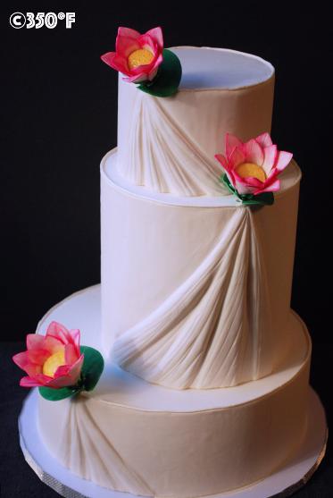 A white wedding cake with pleats and lotus. A cake that gives the impression of a wedding gown.